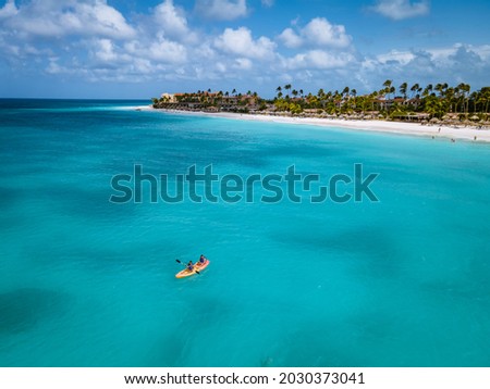 Couple Kayaking in the Ocean on Vacation Aruba Caribbean sea, man and woman mid age kayak in ocean blue clrea water white beach and palm trees Aruba