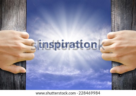 Inspiration text in the blue sky behind hand opening a wooden door.