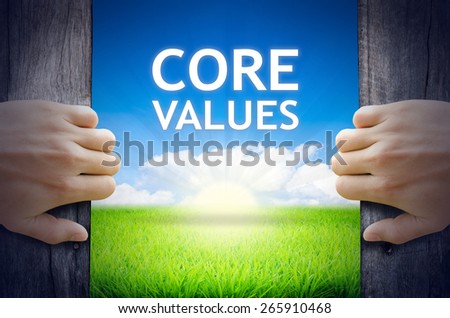 Core Values. Hands opening a wooden door then found a texts floating among new world as green grass field, Blue sky and the Sunrise.