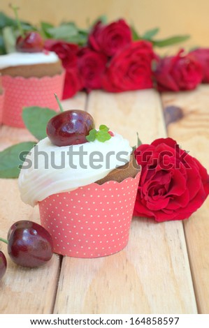 delicious cupcake with a dark chocolate, cherry and red roses