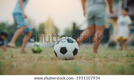 Action sport outdoors of a group of kids having fun playing soccer football for exercise in community rural area under the twilight sunset.