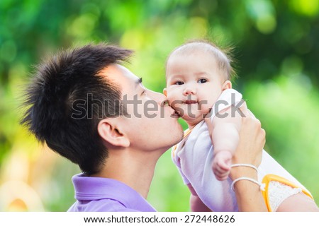 father kiss his 6 months baby, they look so happy in the garden