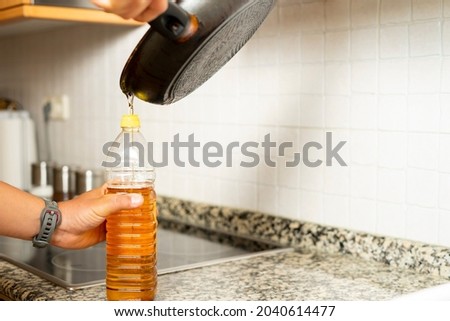 Close up of a man's hands recycling edible oil from a frying pan into a plastic bottle in his home kitchen. Recycling concept at home. . High quality photo