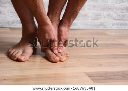 Pain in the foot, man holds hands to his feet, foot massage, cramp, muscular spasm, red accent on the foot, close-up Stok fotoğraf © 