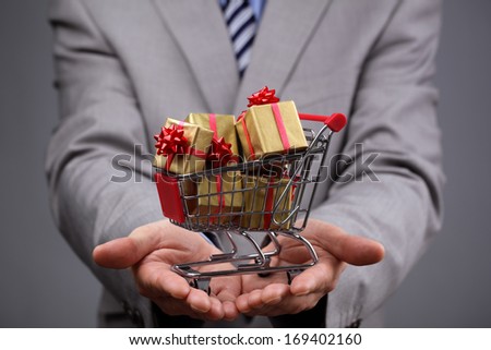 Businessman with shopping cart full of gift boxes concept for gift shopping, business gift, christmas or valentine's day gift