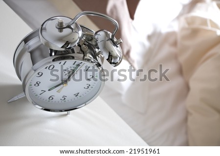 Old fashioned alarm clock and empty bed in the morning