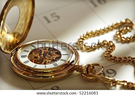 Close up of a gold pocket watch on a calendar in sunlight