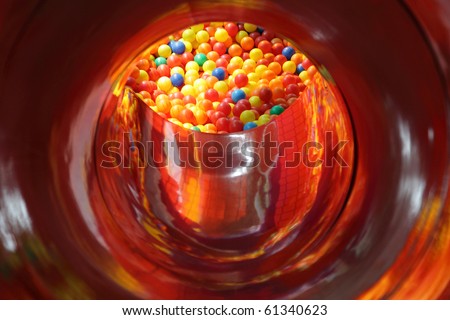 Viewing a personal perspective through a red tunnel down to a ball pool of coloured balls