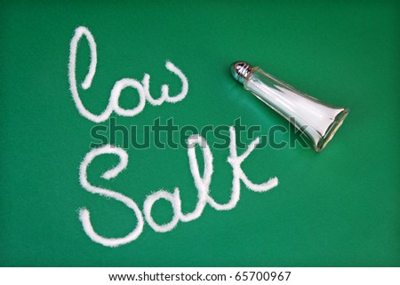 Salt shaker spelling out the words low salt on green background