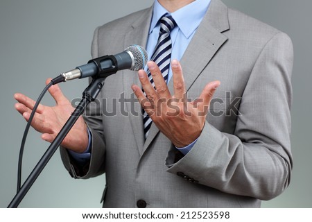 Businessman making speech with microphone and hand gesturing concept for explaining, protesting or belief