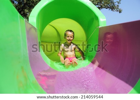 Child sliding down a water slide at a water park smiling and having fun