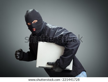 Thief stealing laptop computer concept for hacker, hacking, security or insurance