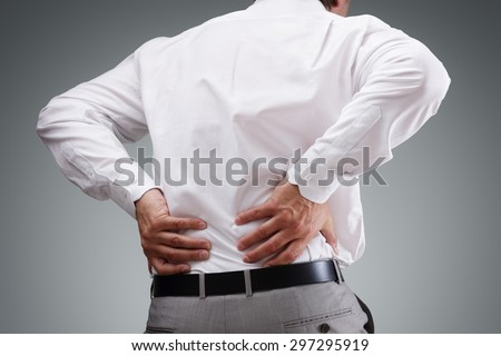 Backache concept bending over in pain with hands holding lower back