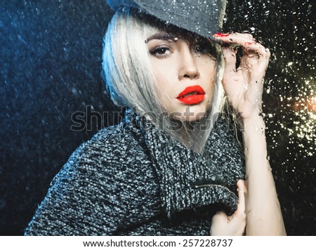 Beautiful woman looking through the window with rain drops