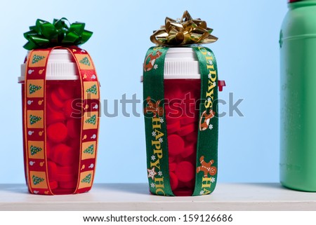 Two pills bottles with bows and ribbon sit on a shelf with with other medicine cabinet items.