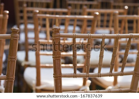 Many empty wooden chairs with white cushion seats.