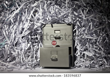 A file cabinet surrounded by lots of shredded paper with a stop sign.