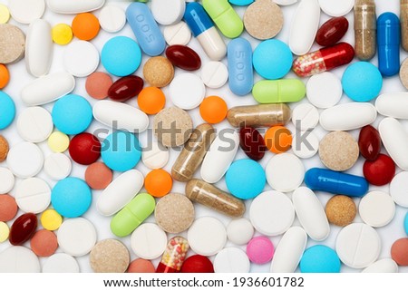 Different colorful medication and pills on white lab table. Creative health care of pharmaceutical concept. Close up of heap of capsules. Flat lay.
