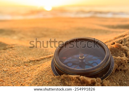 Ancient compass on the sand at the Beach Sunrise ,nature background .