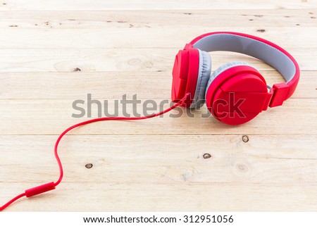 Red Headphones on wood desk Background.
