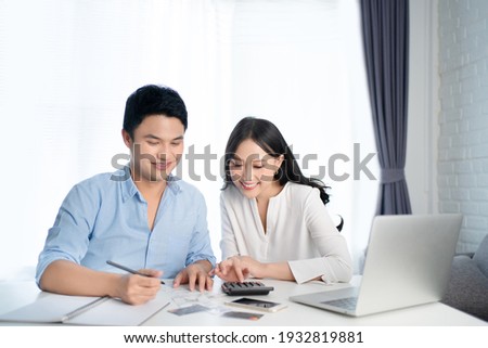 Asian couples are calculating their expenses with a calculator. They are happy.