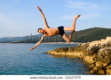 man jumping from rock in sea water and screaming AAA!