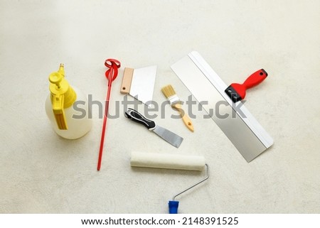 Paint set: roller, brush, spatulas, whisk for plaster, liquid sprayer on the concrete floor, close-up. Repair tools lies on floor Foto stock © 
