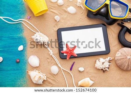 Summer background with summer necessities and digital tablet on the sand.