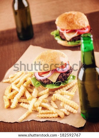 Beer bottles and burgers in the background. Focus is on the burger