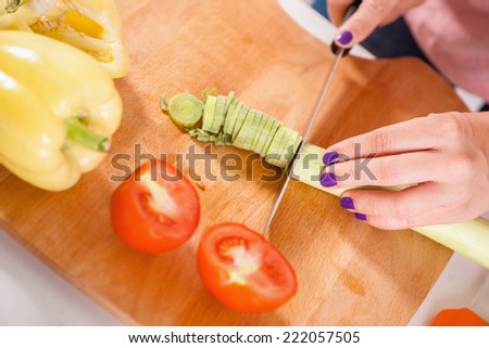 Close Up Of Housewives Hands Slicing Vegetables On Chopping Board