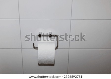 Foto Bild Ersatzrolle Toilettenpapier an der Wand hängend in einer öffentlichen Toilette