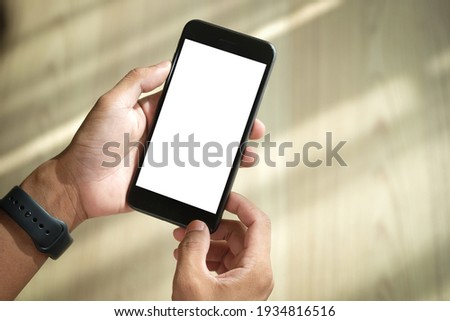 Close up view of male hands using smart phone with modern office blurred background. Blank screen monitor for graphic display montage.