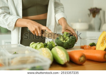 Young sporty woman chopping fresh broccoli on cutting board preparing containers of healthy food. Healthy eating and a balanced lifestyle concept.