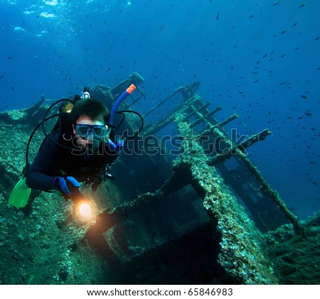 Scuba diver with underwater light  around wreck