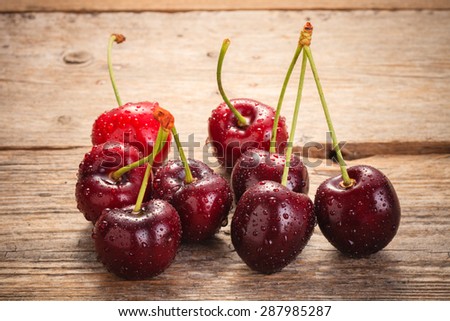 Cherries on wooden rural table with water drops macro background