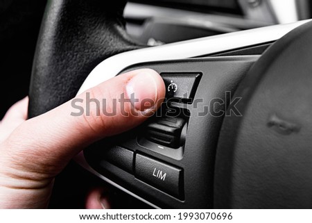 Hand pushes cruise control button on steering wheel. 商業照片 © 