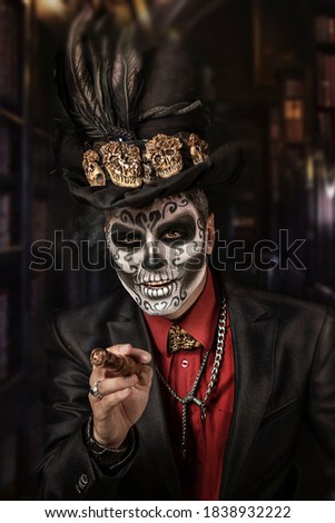  portrait of emotional beautiful man with colorful Halloween skull face painting in top hat with 