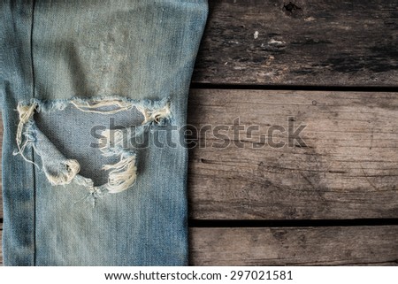 old blue jeans that is a bit torn on wood background