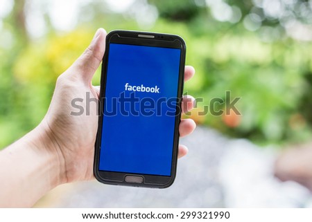 UDON THANI,THAILAND - July 24, 2015: man holding a brand samsung galaxy note 2 with Facebook logo on the screen. Facebook is a social media online service for networking communication.