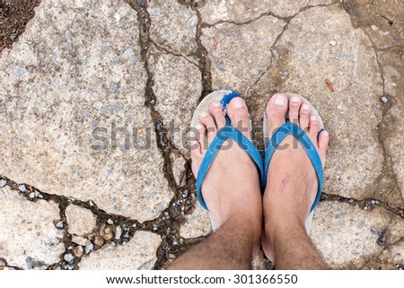 Male foot in flip-flop on street, cracked cement
