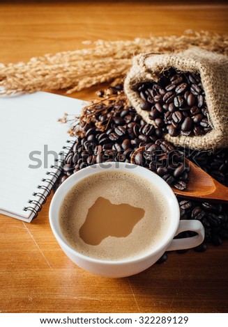 still life of coffee cup ,book and coffee beans on wooden table