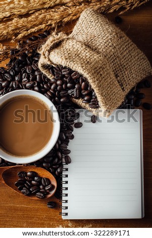 still life of coffee cup ,note book and coffee beans on wooden table,top view