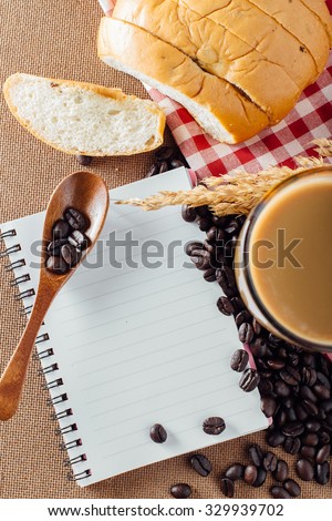 coffee with coffee beans and bread on wooden table