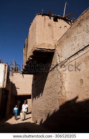 KASHGAR, CHINA - 23 AUGUST 2012 - People walk past a traditional house in Kashgar old town, Xinjiang province, China