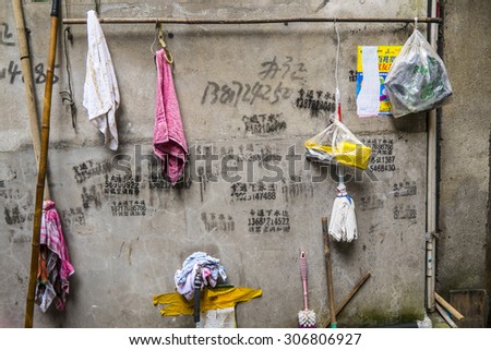 SHANGHAI, CHINA - 17 MARCH 2013 - Phone numbers and household goods adorn an alley wall, Shanghai