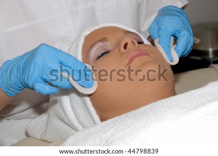 Skincare facial treatment at day spa being preformed on face of woman wrapped in a towel.