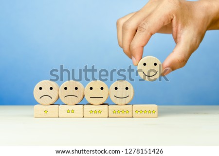 Customer service evaluation and satisfaction survey concepts. The client's hand picked the happy face smile face icon and five star symbol on wooden cube on table Stockfoto © 