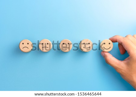 Customer service evaluation and satisfaction survey concepts. The client's hand picked the happy face smile face icon on wooden cube on blue background. copy space Stockfoto © 