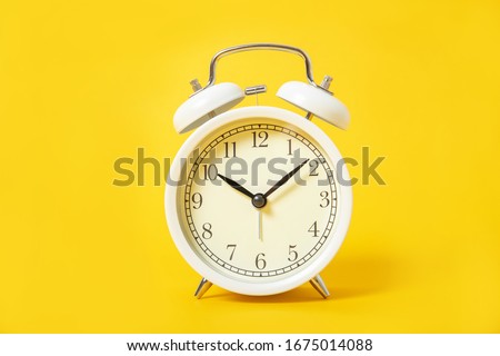 White alarm clock on a yellow background.