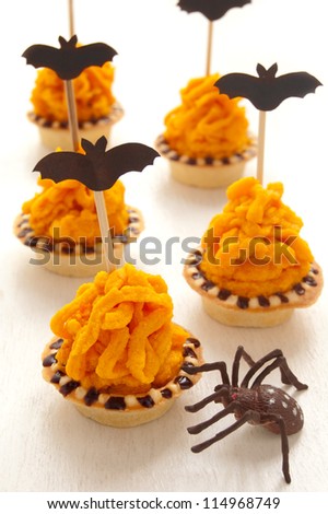Halloween cake with orange cream decorated with a bat on a stick